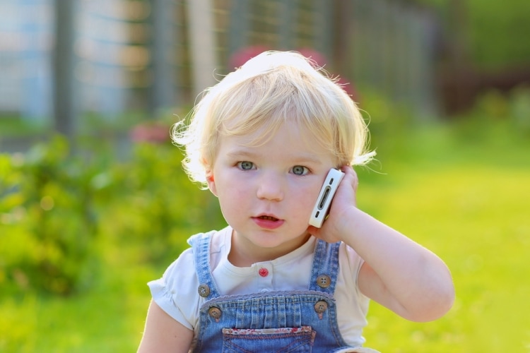 Мобильный телефон для первоклассника - маленькая девочка разговаривает по мобильному телефону